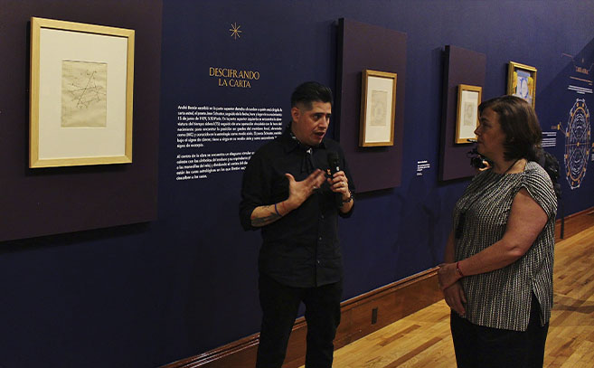 El curador David Caliz explica a la directora del INBAL Alejandra de la Paz, la carta astral de Breton