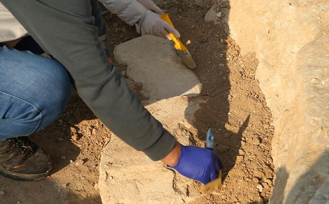 Un arqueólogo retira con cuidado la tierra de una estructura de piedra
